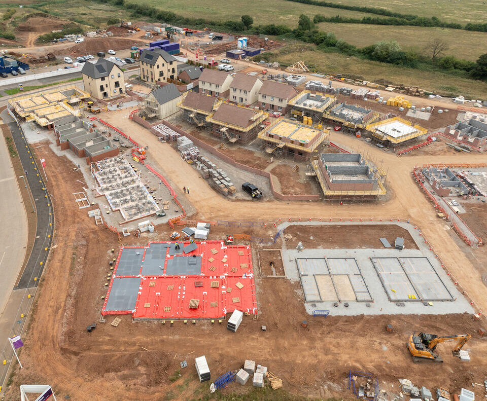 This drone photo shows the progression of a new build housing estate. In the bottom half of the image are new foundations, at the top of the image are newly completed homes.