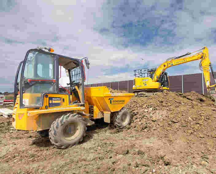 A yellow dumper and a large yellow digger on a pile of earth