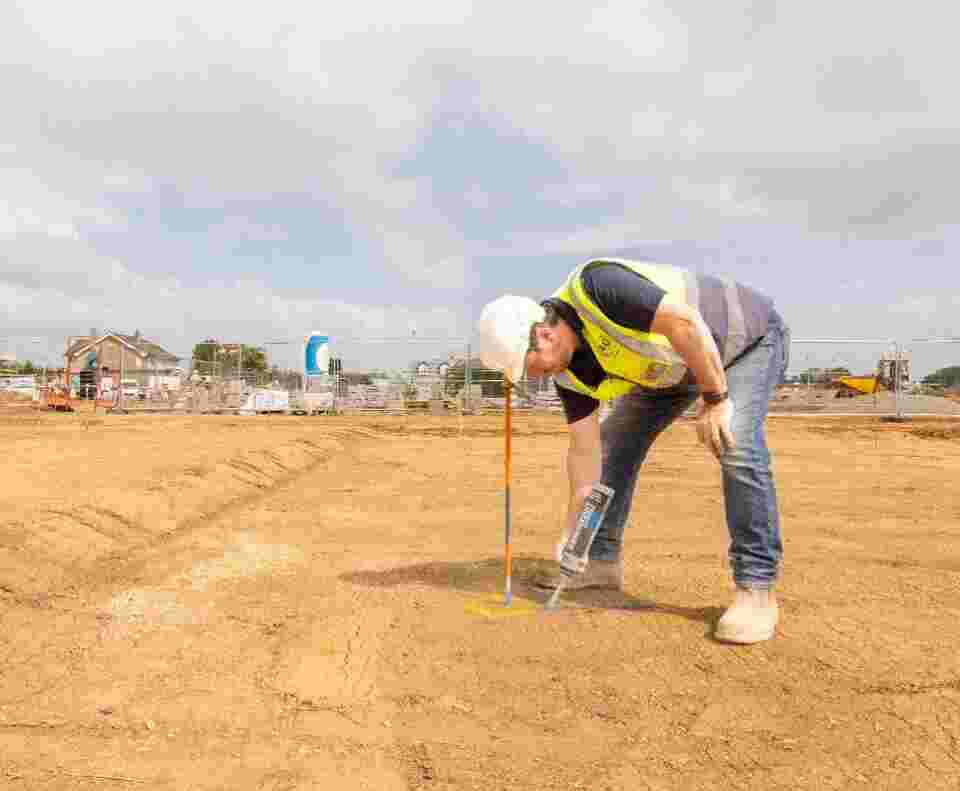 A groundworker is using a spray can on the ground.