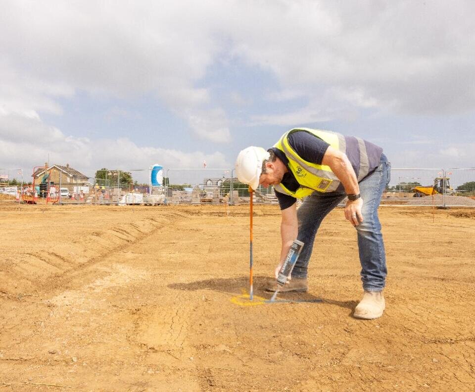 A groundworker is using a spray can on the ground.